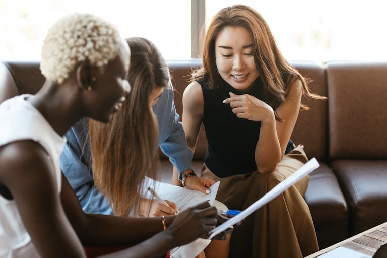A diverse group of women engage in a collaborative business meeting in an office setting.